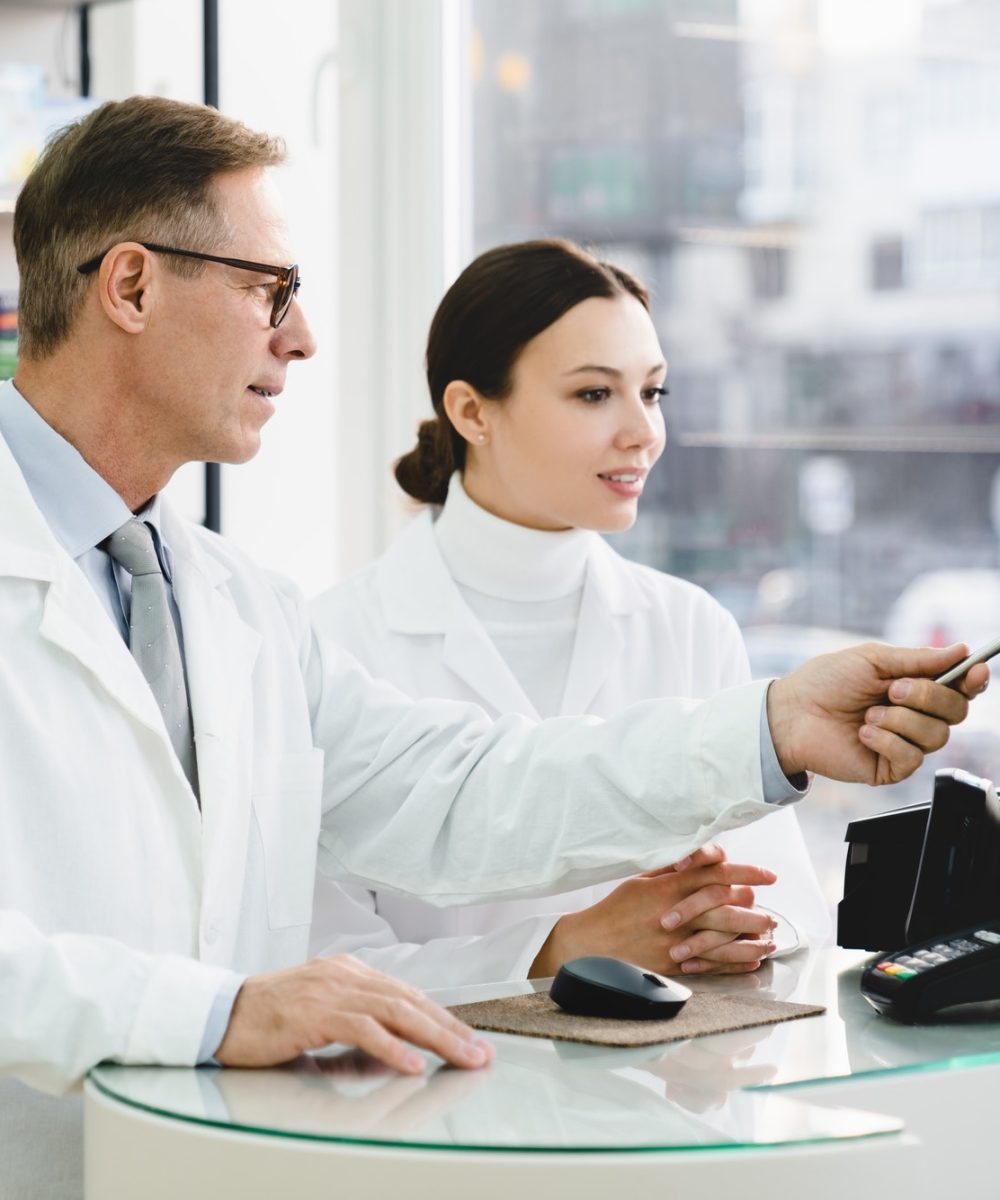 pharmacist-pointing-showing-male-colleague-medication-prices-prescriptions-on-computer-screen.jpg